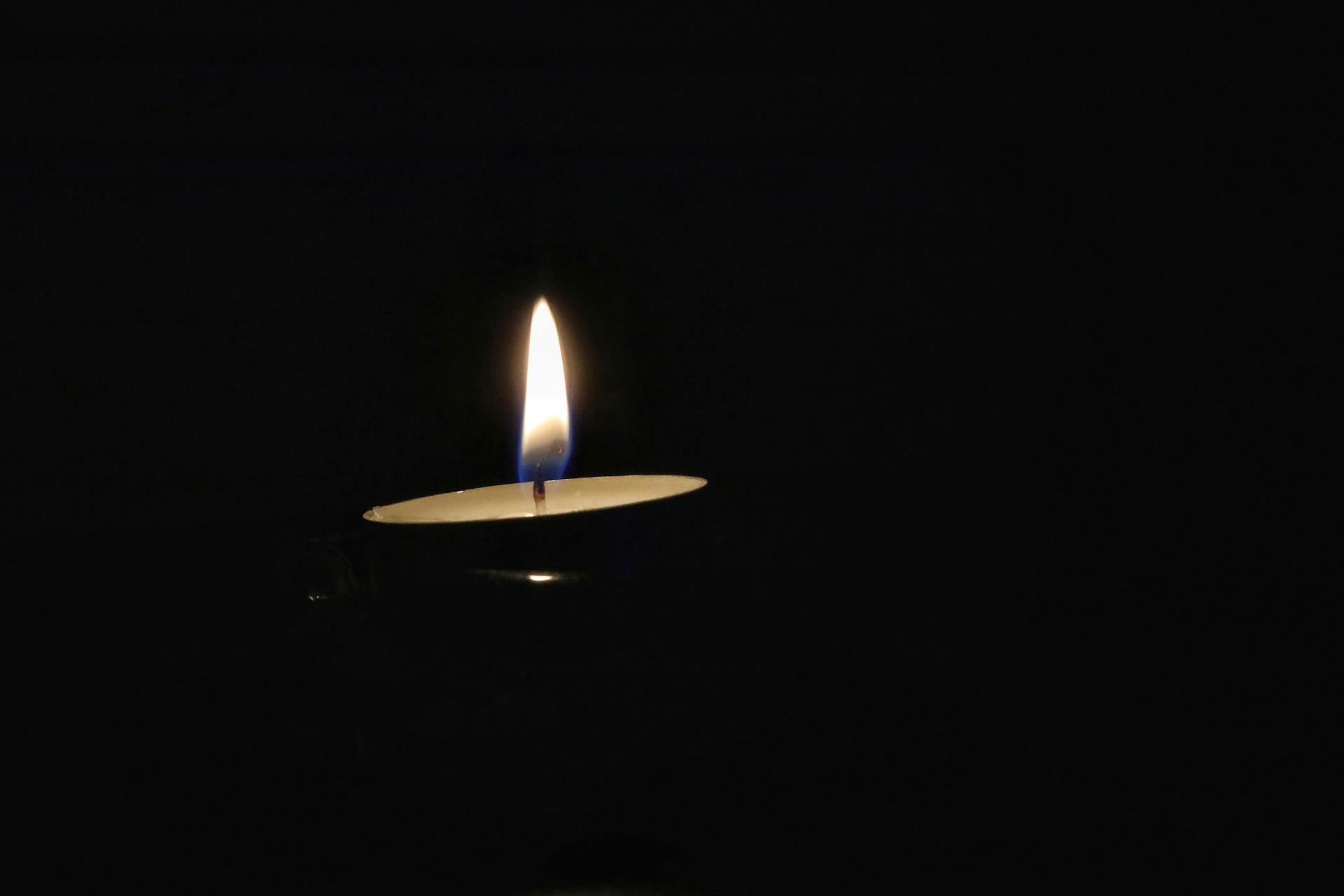 Einzelne Kerze im dunklen Raum — ein Licht in der Nacht