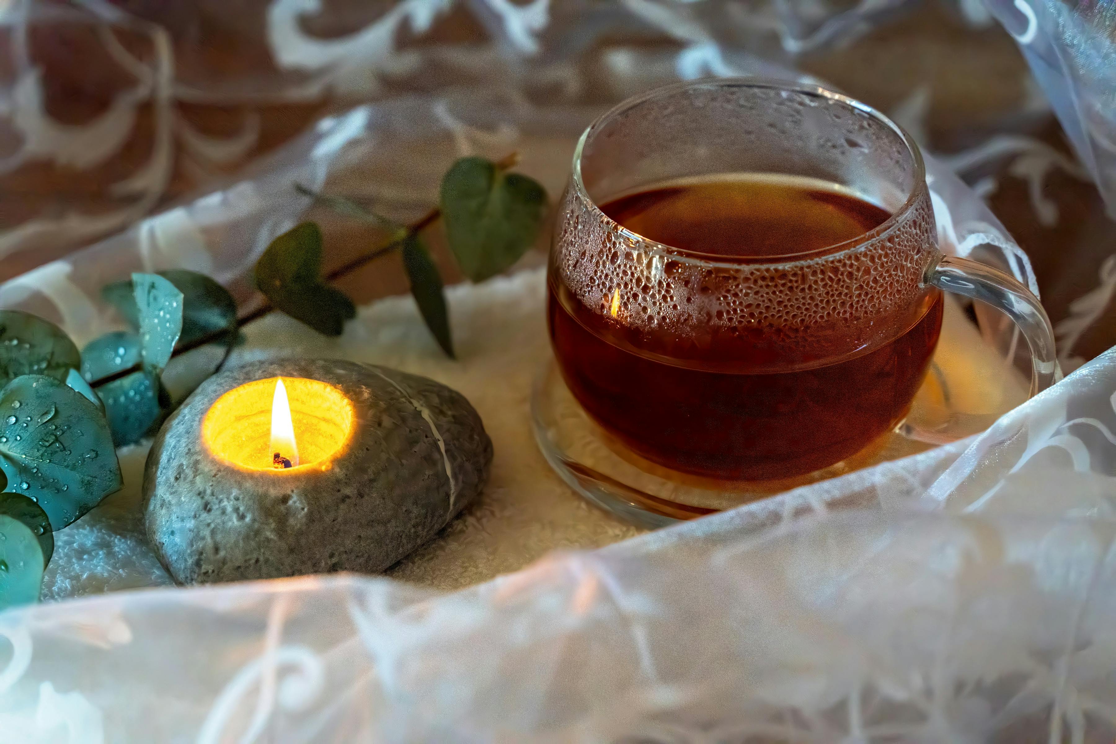 Tee und Kerze auf einem Holztisch in stiller Atmosphäre — Heilung im Kleinen