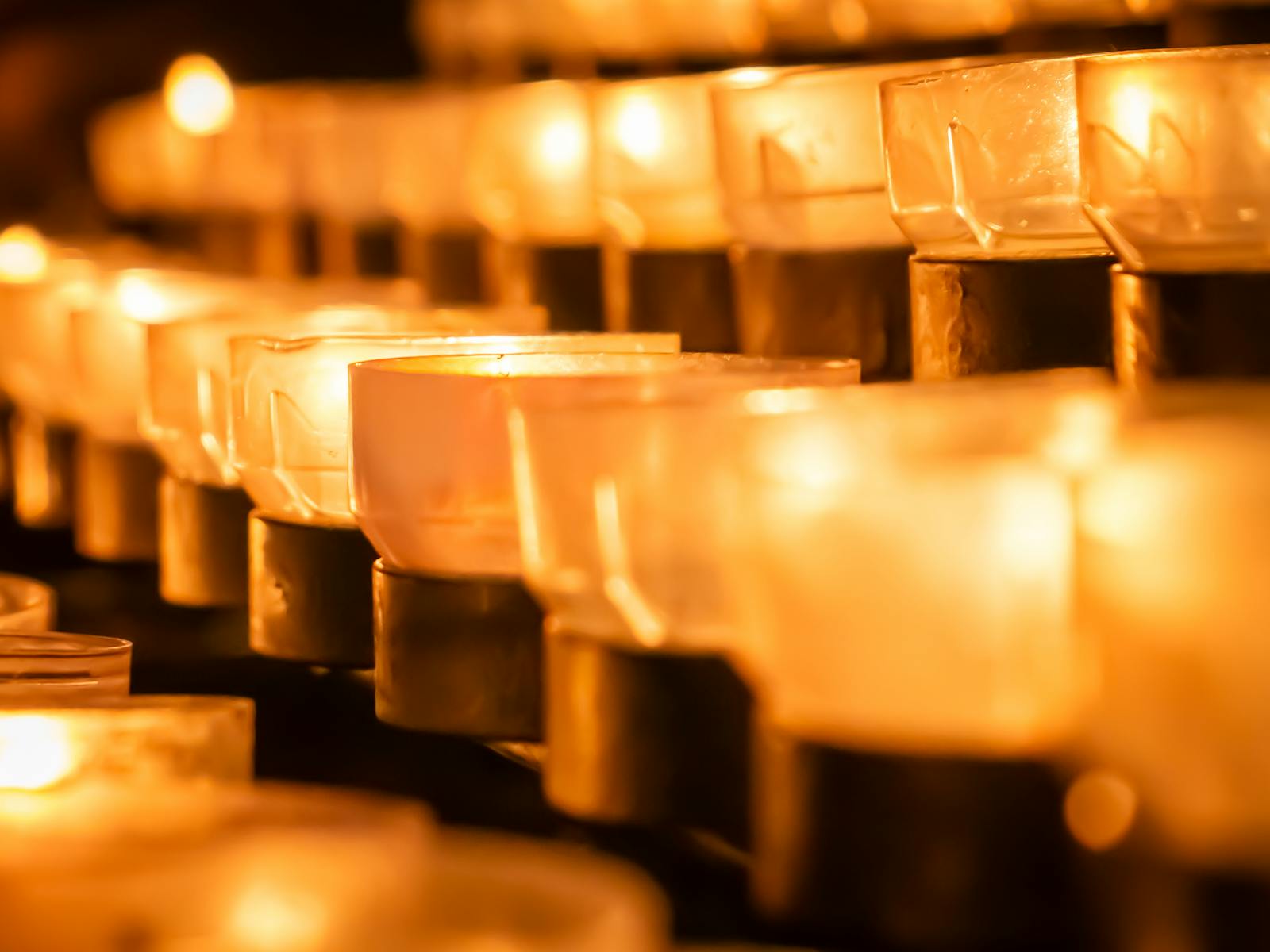 Reihen von Kerzen leuchten in einer dunklen Andacht — Symbol für die heilige Stille der Nacht